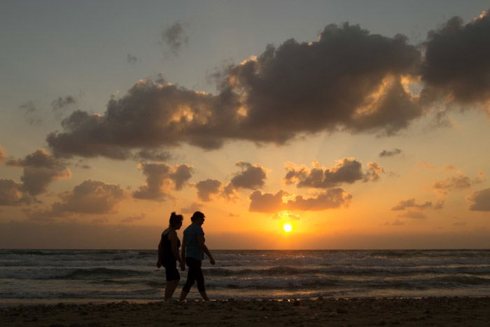 A couple walking on the beach at sunset.