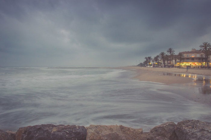 A coastal seascape photographed during a storm with a beach house to the right of the frame