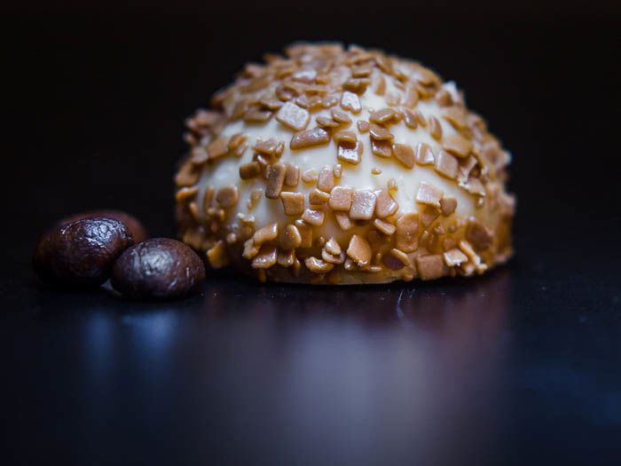 A praline with two coffee beans to its left