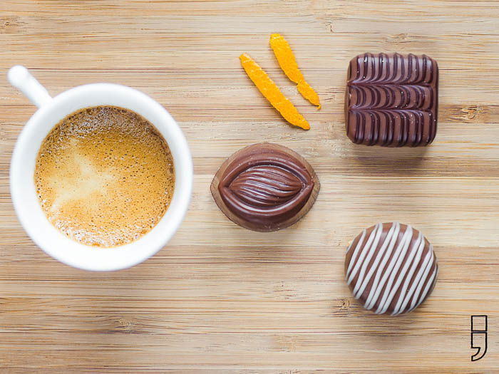 A cup of coffee with pralines on a wooden plate