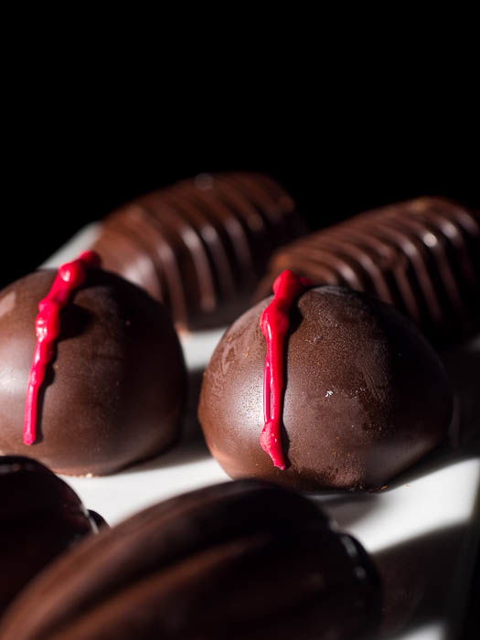 Closeup image of pralines on a white plate in front of a black background