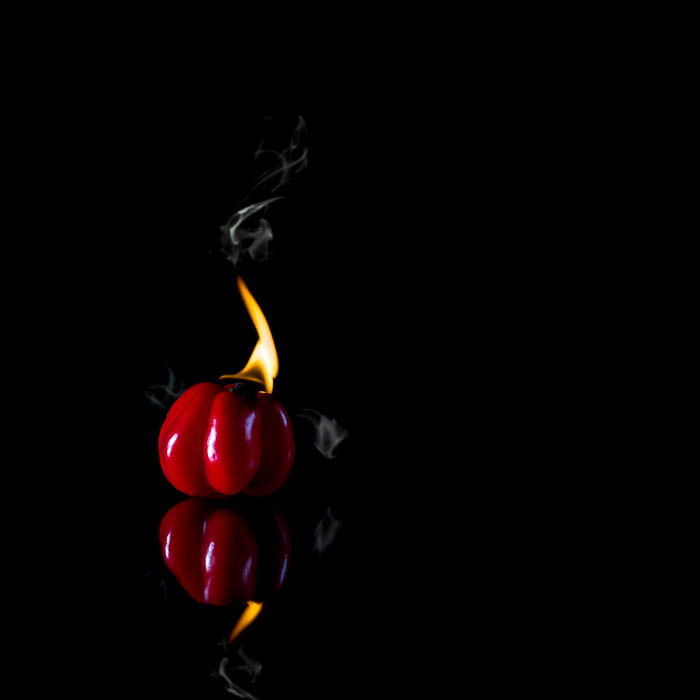 Creative food photo of a red pepper thats so hot it's on fire