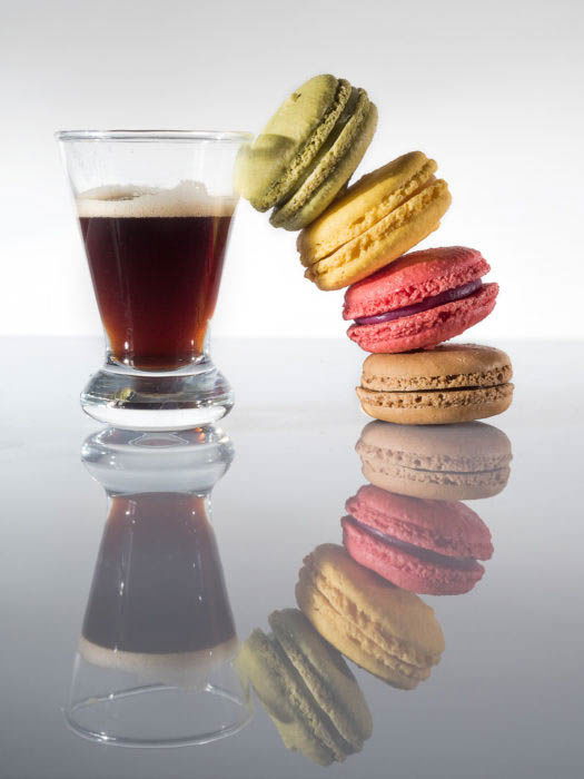 A stack of rainbow macarons beside a coffee cup