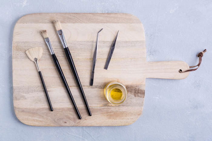 brushes and tweezers for food photography arranged on a wooden board