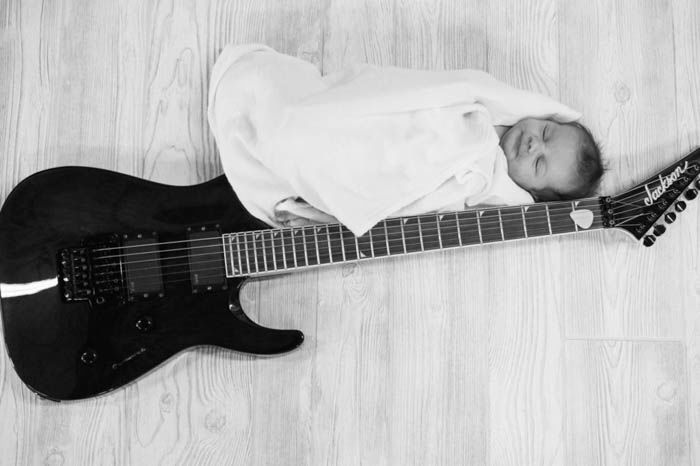 newborn baby poses next to a guitar