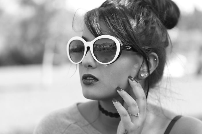 Black and white product photography headshot of a model with a reflection in white-framed sunglasses