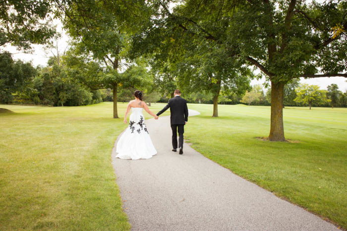 A bride and groom posing outdoors walking away from the camera 