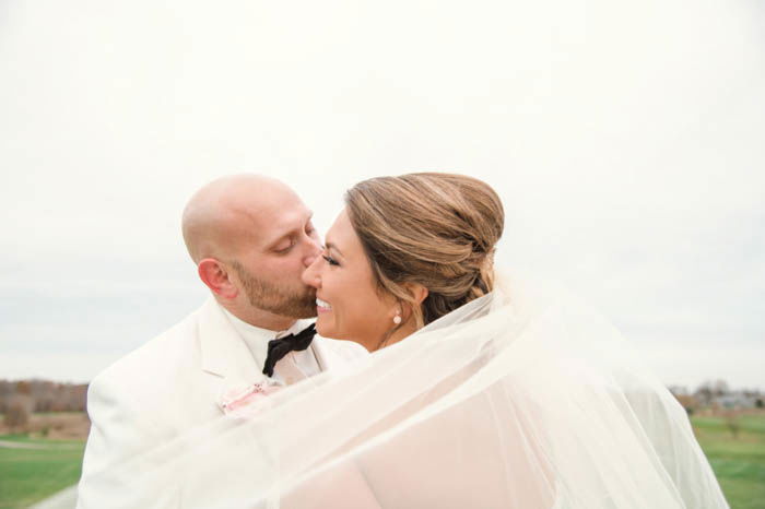 Wedding portrait of the couple posing outdoors with the veil 