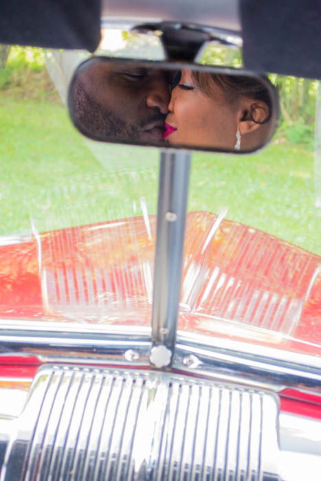 Car mirror reflection of a newlywed couple kissing