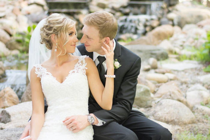 A bride and groom posing outdoors seated down 