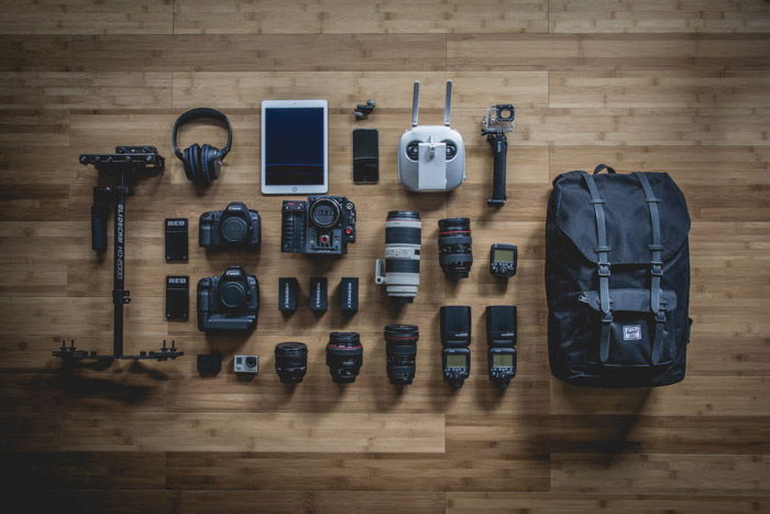 a flay lay of a camera bag and its equipment spread on a wooden table