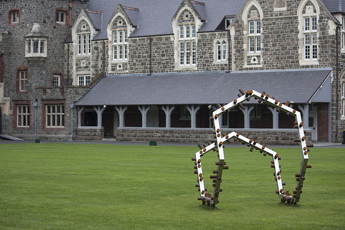 Photo of Anton Parsons artwork 'Acquiesce' on the grass outside a large stone building. Architecture Photography.