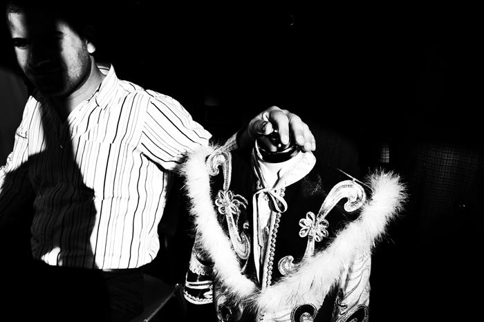 black and white street portrait from Istanbul, a man rests his hand on a shop mannequin traditional costume. 