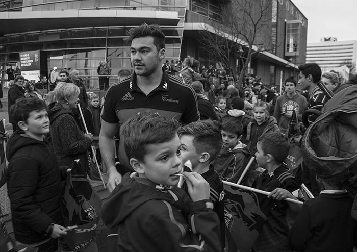 Blavk and white street photography of a crowd surrounding their winning rugby team.