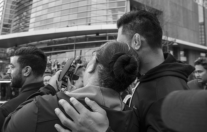 Black and white photo of a couple taking a selfie in a busy street scene. Creative street photography