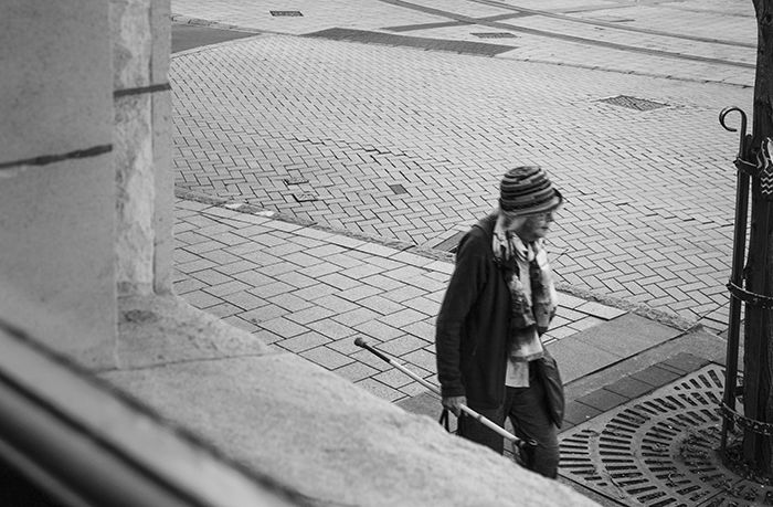 Black and white photo of a woman in framed taken from inside a window. Creative street photography