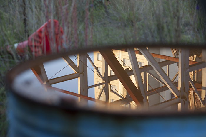 Photo of an industrial building scene reflected in the water of a blue barrel. Creative street photography