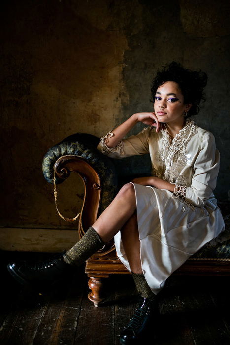 Portrait of a young woman in white sitting on a green couch by Tasneem Alsultan. 