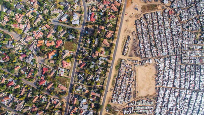 Johnny Miller aerial photography of a densely populated area vs the sparser, and greener area to the left