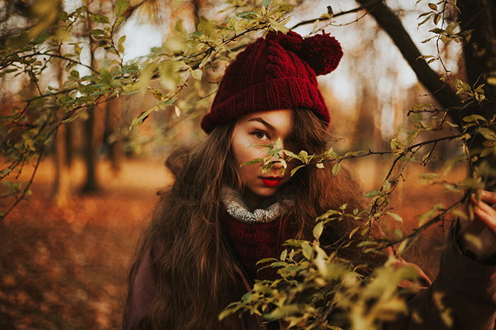 portrait of a girl in red hat looking through trees on a beautiful autumn day - natural light portraits