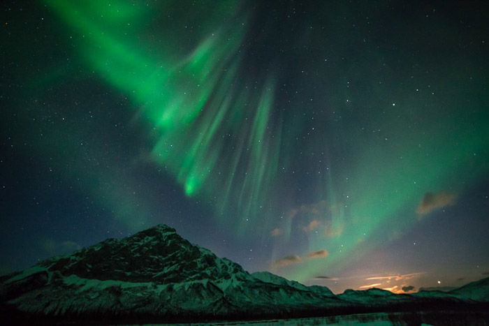 Stunning landscape with northern lights and starry sky above a mountain. 