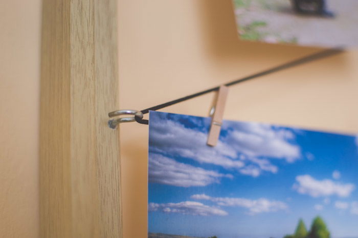 A photograph hanging by a small wooden peg elastic string and a clothespin attached to a wood frame as an idea of what to do with photos