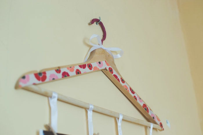 A painted wooden clothes hanger on the wall as an idea for a mobile as an idea for what to do with photos