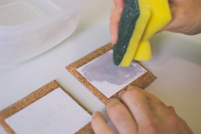 A close-up photo of wetting photo paper on coasters with a sponge as an example of what to do with photos