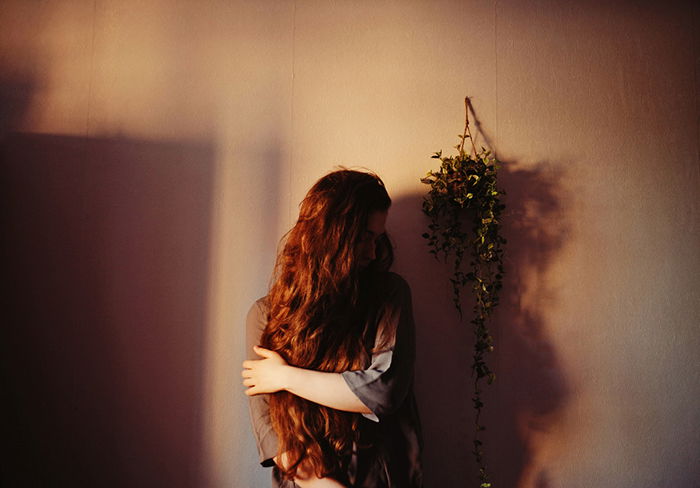 Shjadowing portrait of a woman standing against a wall