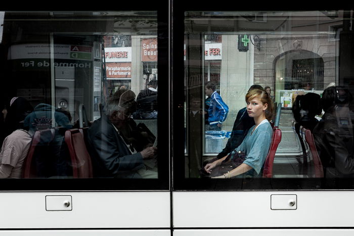 View of a tram window with a young lady looking straight at the camera. Urban photography