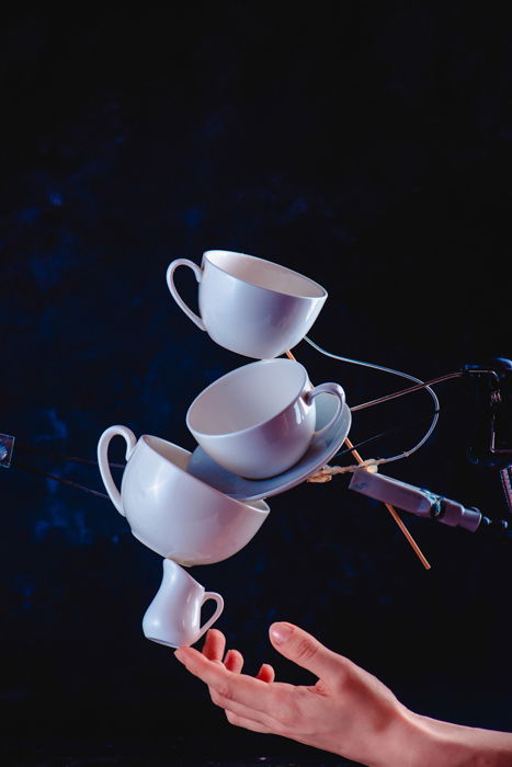 A creative coffee splash photography idea of balancing falling coffee cups on dark blue background