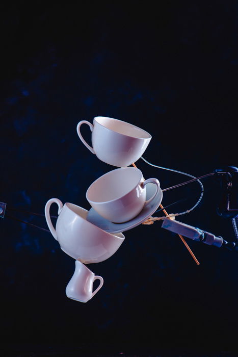 A creative coffee splash photography idea of balancing falling coffee cups on dark blue background