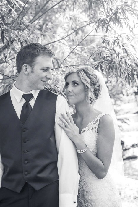 A newly wed couple pose under a tree, shot in b&w