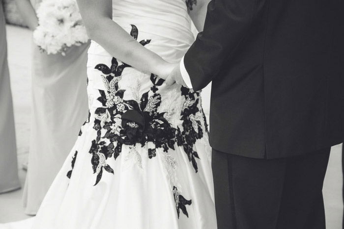 A close up black and white wedding shot of a couple holding hands