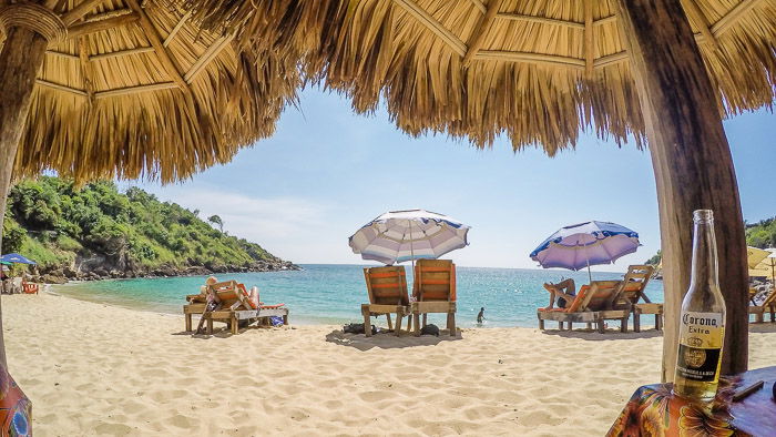 A pretty beach scene framed by straw umbrellas - travel photography jobs