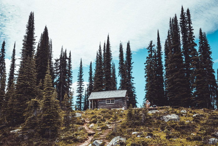 A bright photo of cabin on a hill surrounded by tall trees - how to make money with travel photography