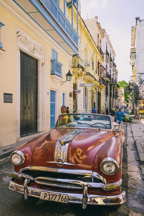 A red car parked on a street in Cuba - how to make money with photography