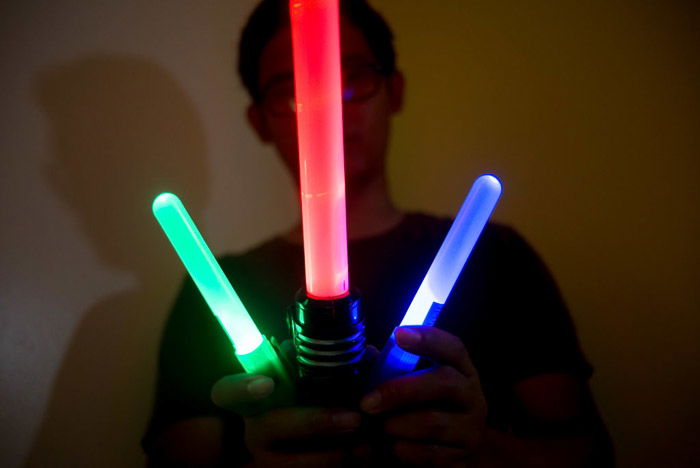 A man holding three colored light sticks for light painting photography