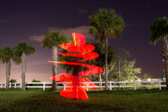 A palm tree surrounded by a red light spiral of light painting