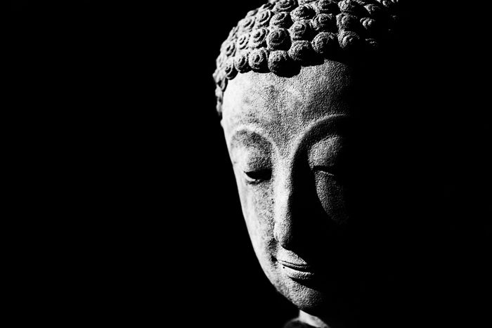 A low key monochrome photography portrait of a statue of buddha.