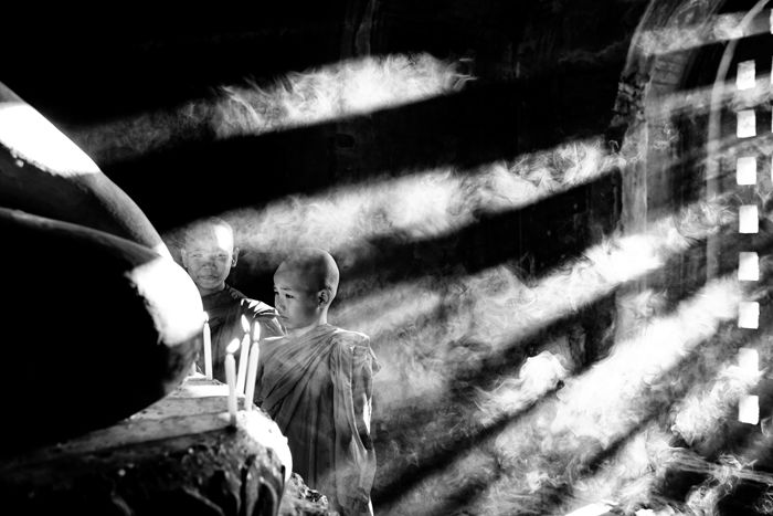 A low key monochrome photography shot of young Buddhists in a temple