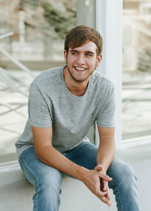 An outdoor portrait photography shot of a young man posing casually