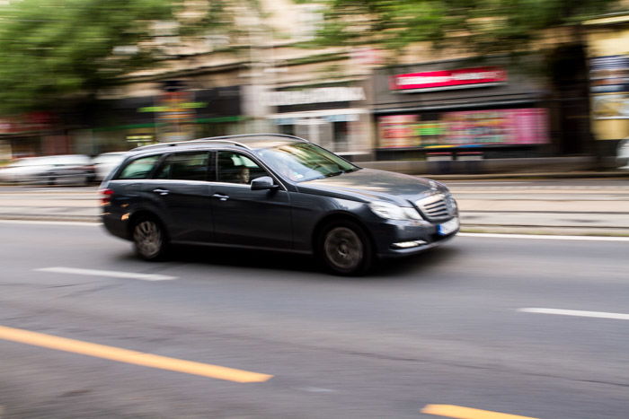 A blurry shot of a grey car driving on the street