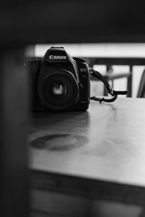 Black and white photography of a canon dslr on a table.