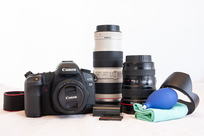 A still life of a canon camera and other photography equipment on a white background.