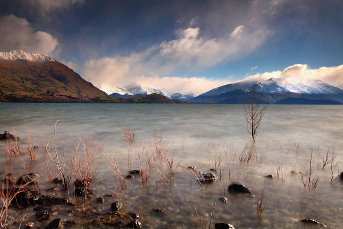 Long exposure photography of water in the foreground of a mountainous landscape - travel photography checklist