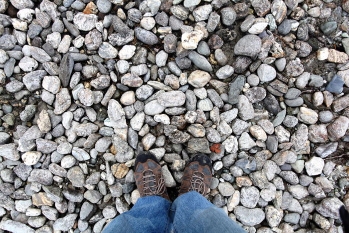 Overhead photo of a stony ground with the photographers feet- travel photography checklist.