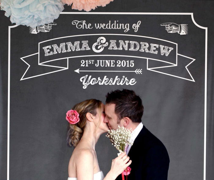 an image of a newly wed couple kissing against a chalkboard photo booth