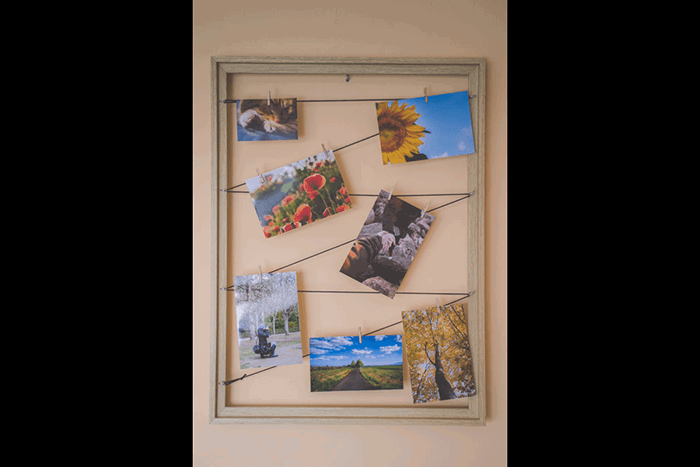 Multiple photos hanging form elastic string in a wood frame as an idea for what to do with photos