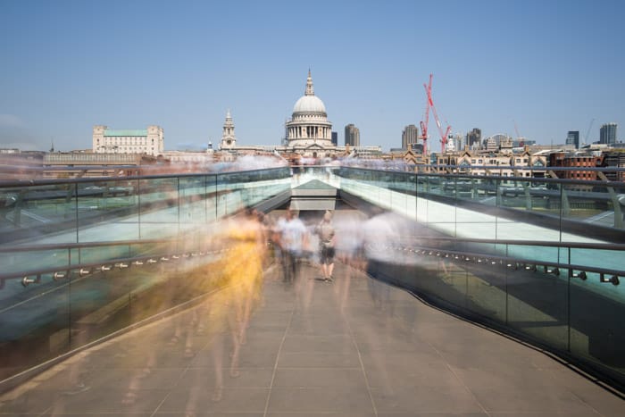 A time lapse photography shot of the blurred figures of people walking out of an underground passage